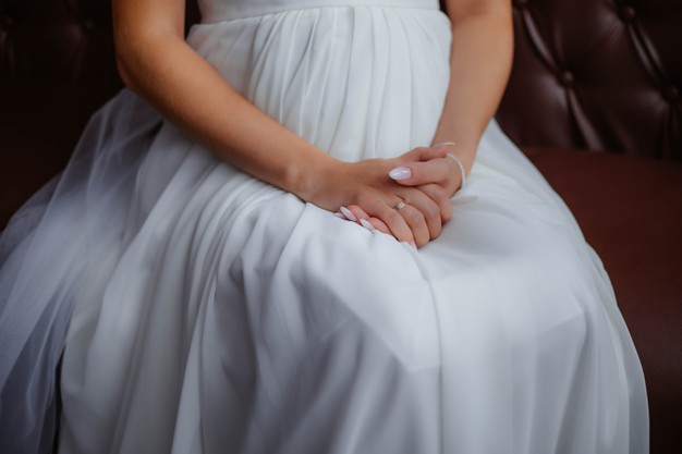 girl-white-dress-is-sitting-soft-armchair-holding-her-hands-her-lap-hands-bride-white-dress-bride-wedding-morning_152904-7661